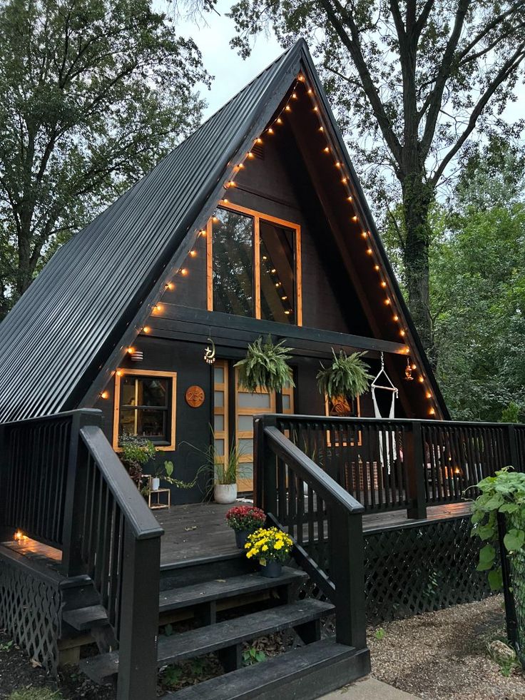 a - frame cabin in the woods with lights on it's roof and stairs