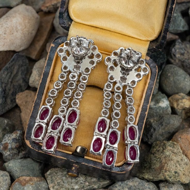 These lovely dangle style pierced earrings are each accented with three (3), prong set, baguette cut diamonds, thirty-three (33), prong set, round brilliant cut diamonds and six (6), prong set, oval mixed cut natural rubies. The earrings measure 42mm X 15mm and are finished with friction style backs. Formal Baguette Cut Diamond Earrings With Diamond Accents, Formal Baguette Cut Diamond Earrings With Accents, Platinum Baguette Diamond Earrings For Wedding, Elegant Baguette Cut Single Diamond Earrings, Wedding Platinum Earrings With Baguette Diamonds, Formal Baguette Cut Diamond Earrings With Single Cut Diamonds, Baguette Cut Diamond Earrings For Formal Events, Baguette Cut Diamond Earrings For Formal Occasions, Evening Single Cut Diamond Dangle Jewelry