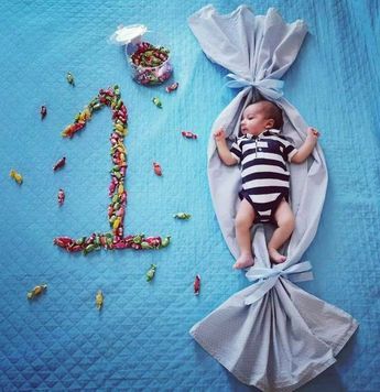 a baby laying on top of a blue blanket next to candies and a candy bag