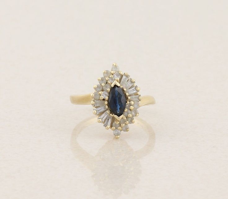 a yellow gold ring with a pear shaped blue sapphire surrounded by small white diamonds