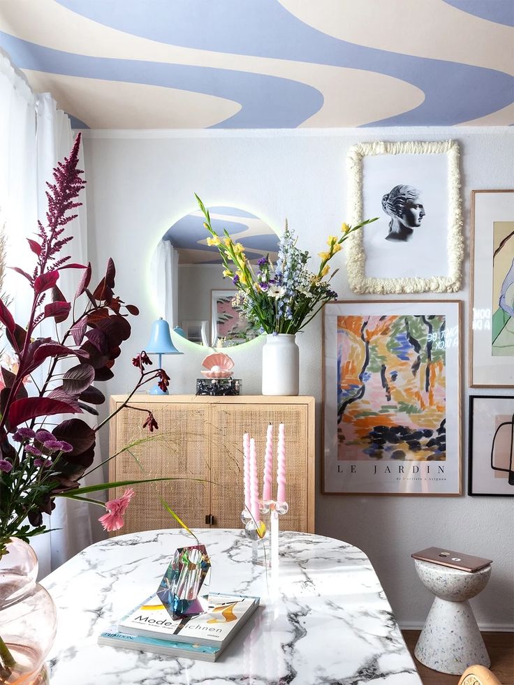 a dining room table with flowers and pictures on the wall