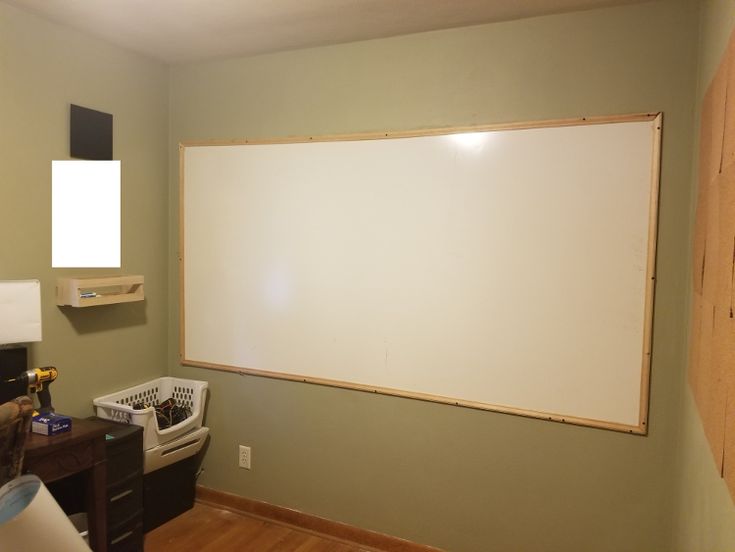 an empty room with a large whiteboard on the wall and other items around it