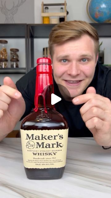 a man holding up a bottle of maker's mark whisky in front of his face