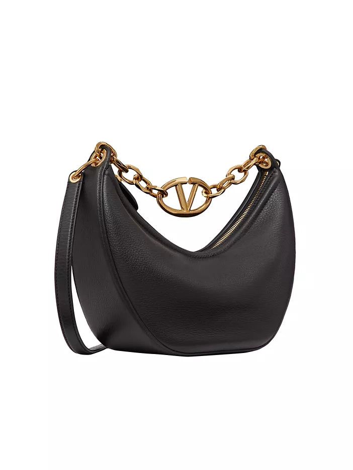 Valentino Garavani Moon small hobo bag in leather with chain and metal VLogo signature detail. Equipped with a chain and detachable leather shoulder strap, the bag can be worn as a crossbody/shoulder bag or carried by hand. Gold tone-finish chain and hardware Removable leather strap Zipper closure Nappa leather lining. Interior: one slip pocket Made in Italy SIZE Shoulder strap drop length: 55 cm / 21.7 in. Chain drop length: 22cm / 8.6 in. Dimensions: W 29 x H 23 x D 11 cm / W 11.4 x H 9 x D 4. Evening Shoulder Bag With Metal Logo, Chic Shoulder Bag With Metal Logo For Everyday Use, Chic Crossbody Shoulder Bag With Metal Logo, Chic Shoulder Bag With Metal Logo For Evening, Designer Shoulder Bag With Chain Detail, Designer Shoulder Bag With Chain, Luxury Evening Hobo Bag With Detachable Strap, Luxury Shoulder Bag With Chain In Crossbody Style, Luxury Hobo Bag With Gold-tone Hardware For Evening