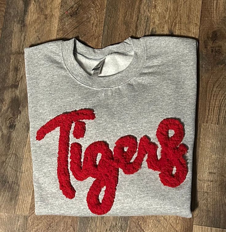 Show your school spirit in this cute sweatshirt. Comfort, casual and loose fitting, made on 50/50 cotton/poly blend shirts.  Embroidered chenille yarn, Tigers sweatshirt.  Please message us if you have a custom color request and we will create a separate listing for custom requests.  You can follow us at the below link for chances to win giveaways and to see all of our latest creations.  https://www.facebook.com/groups/710060383256657/?ref=share&mibextid=S66gvF Kentucky Sweatshirt, Purple Cat, Cat Sweatshirt, Cute Sweatshirts, Blue Cats, Grey Sweatshirt, School Spirit, Custom Color, Loose Fitting