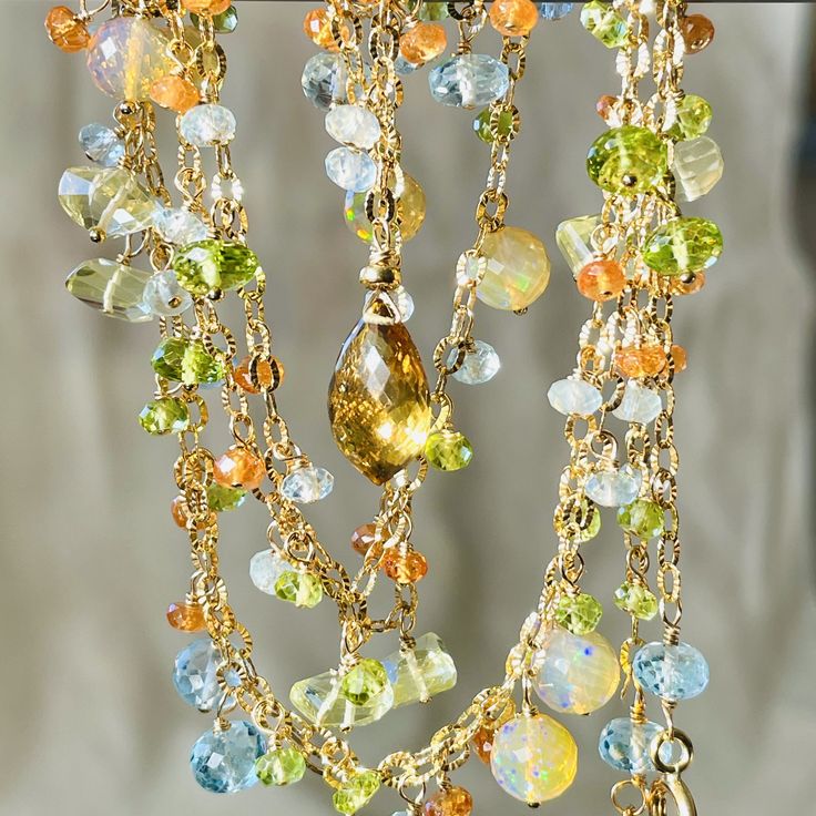 One of a kind, bohemian style, long and luxurious subtly hued lariat. This gold filled necklace is created with shimmery, textured chain adorned with lots and lots of dangles of mixed color, shape and size  beautiful faceted, exquisite quality gems. These gems are: whiskey quartz briolette, rounds of fiery Ethiopian opal, roundels of sky blue topaz, peridot and lemon quartz and smaller roundels of aquamarine, peridot and Spessonite, orange garnet. Arranged all around of the length of the necklac Bohemian Lariat Necklace With Gemstone For Jewelry Making, Bohemian Gemstone Lariat Necklace, Bohemian Lariat Necklace With Gemstone, Bohemian Citrine Gemstone Necklace, Bohemian Yellow Gold Briolette Jewelry, Bohemian Yellow Gemstone Jewelry, Bohemian Multicolor Briolette Jewelry, Lemon Quartz Necklace, Gold Filled Necklace