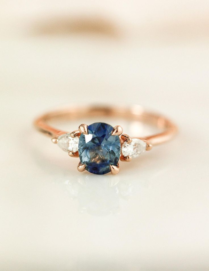 a blue and white diamond ring with three diamonds on it's side, sitting on a table