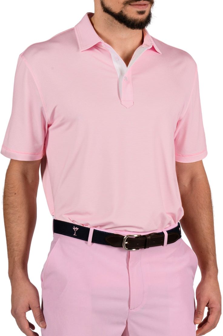 a man wearing a pink polo shirt and black belt with his hands in his pockets