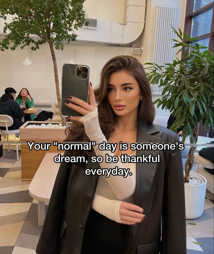 a woman taking a selfie with her cell phone while wearing a black leather jacket