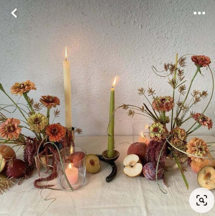 an arrangement of flowers, apples and candles on a white tablecloth with text overlay