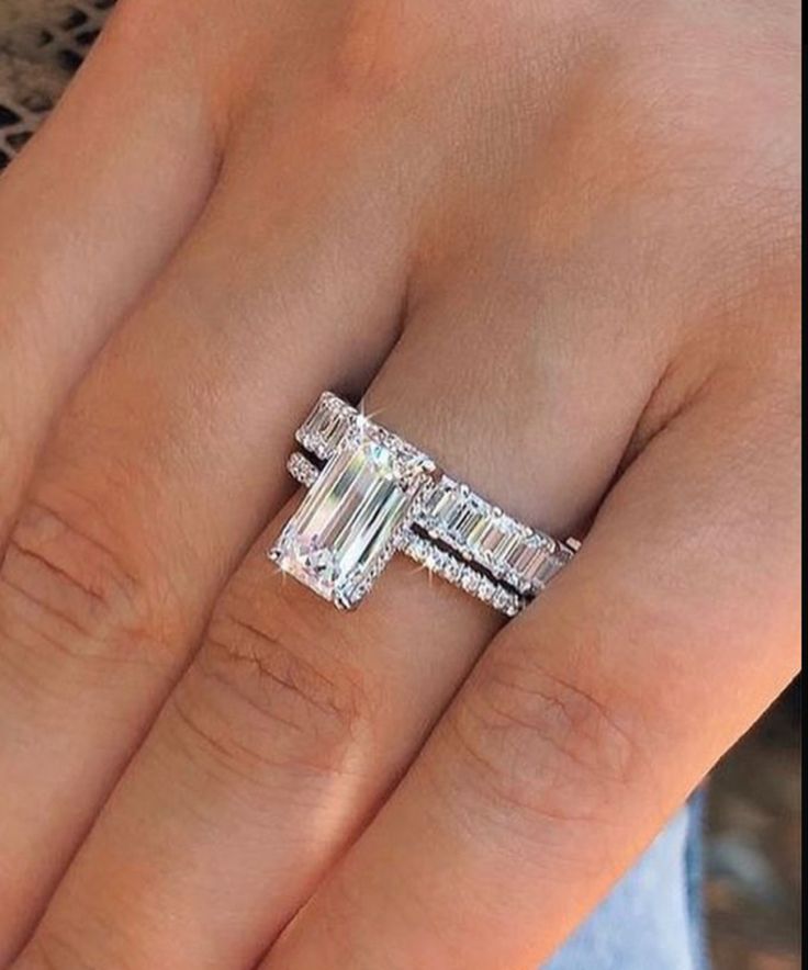 a woman's hand with an engagement ring and two wedding bands on her fingers