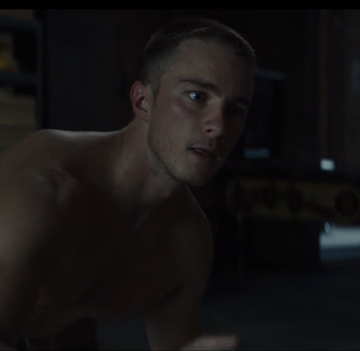 a shirtless man standing in a dark room