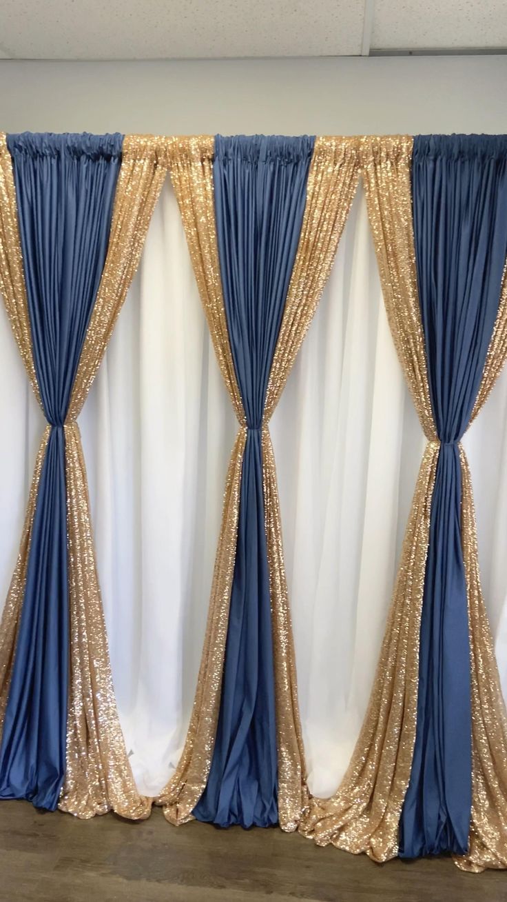 gold and blue drapes are hanging on the wall next to a white curtain with sequins