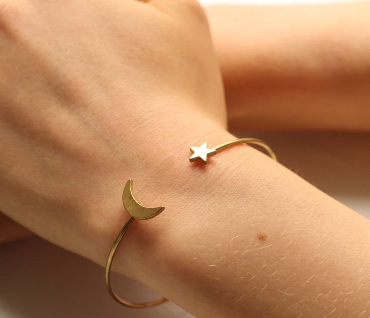 This wonderful bracelet or bangle features a simple crescent moon, teamed with a little star.  The front of the bracelet is open, which means it can be easily squeezed or stretched to fit most wrists.   The bracelet is made from solid brass, which is a very strong and flexible metal!  The brass has darkened over time to a rich golden bronze colour.   The bracelet band is fairly fine, measuring 3mm thick.  The crescent moon measures approximately 15mm.   This piece of handmade jewellery comes packaged in a nice recycled gift box with a handmade tag, all ready to give or keep. 🖤 FASTER SHIPPING 🖤 Need this fast? We offer a Faster Shipping option here: https://www.etsy.com/uk/listing/100107311/faster-shipping-priority-post-upgrade 🖤 GIFT MESSAGE & WRAP SERVICE! 🖤 If you would like these s Simple Crescent Moon, Sun Bracelet, Bronze Colour, Jewelry Star, Moon Bracelet, Handmade Tags, Celestial Jewelry, Star Bracelet, Moon Star