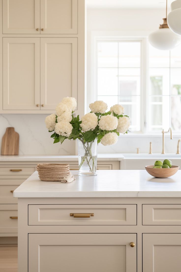 white flowers are in a vase on the kitchen island