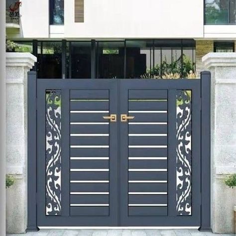 an iron gate with decorative designs on the top and bottom bars, in front of a white building