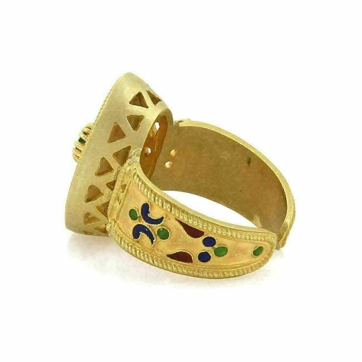 "This lovely vintage ring is crafted from 18k yellow gold with a matte finish. It features a wide cuff band with oval top with multicolor enamel leaf design along the band and on the oval shape design also accented with a round cut emerald gemstone. It has the metal content stamp 750. Material: 18k yellow gold Measurement: top: 0.52\" across x 0.79\" long x 0.31\" high Gemstone: Emerald 3.5mm Ring Size: 6.5 Weight: 9.7 grams 19453-M" Yellow Gold Enamel Cabochon Ring, Yellow Gold Round Cabochon Enamel Ring, Yellow Gold Cabochon Enamel Ring, Yellow Gold Enamel Ring With Cabochon, Gold Enamel Multi-stone Round Ring, Gold Multi-stone Enamel Round Ring, Gold Enamel Multi-stone Ring, Gold Enamel Ring With Multi-stone, Gold Luxury Enamel Ring With Cabochon