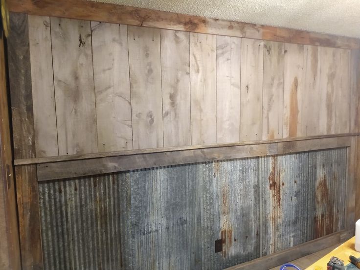 an old wooden paneled wall in a room with tools on the table and paint rollers next to it