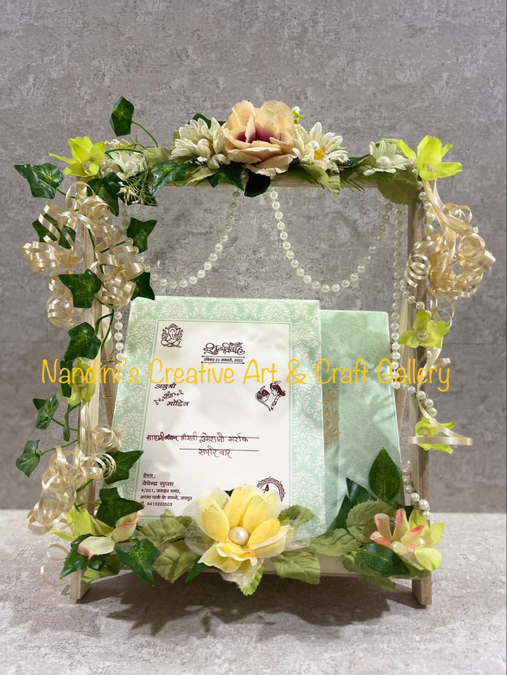 an ornate frame with flowers and pearls on the front is adorned with green leaves, white orchids and pearl beads