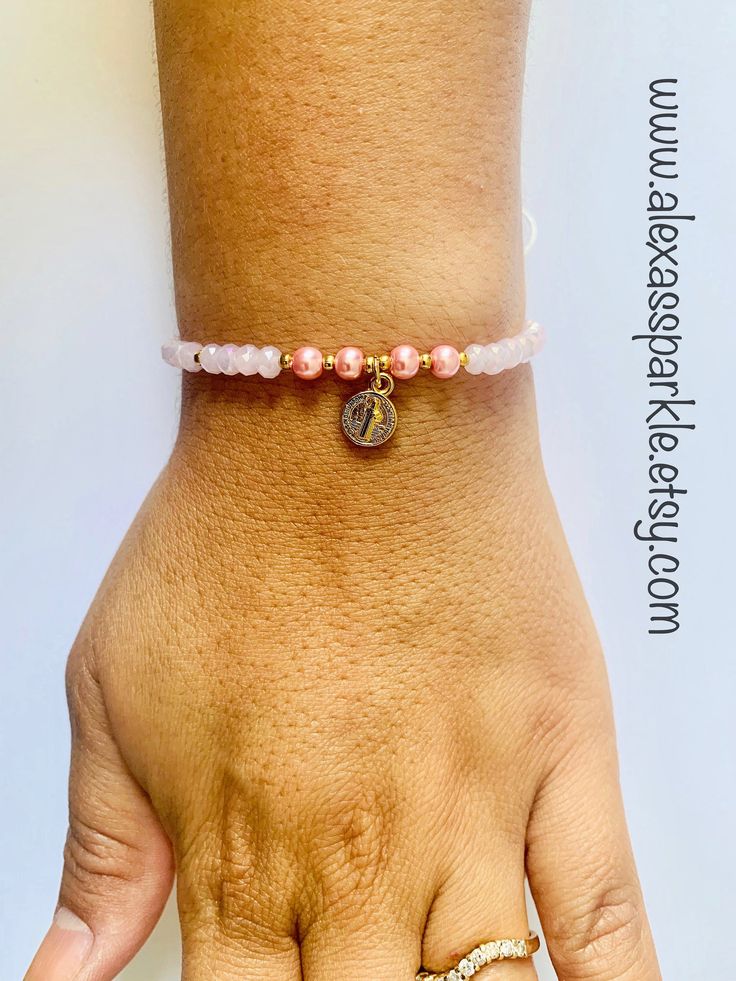 This beautifully handmade bracelet is made of medium (4mm) rose crystal beads and faux pearls with a St. Benedict charm in the middle. The bracelet is made with white thread string with a sliding knot to adjust to the majority of the wrist sizes. These are a great bracelets for everyday wear. This bracelet is beautifully made and is also great for spiritual protection purposes. The purpose of using the Saint Benedict medal is to call on God's blessing and protection upon us, wherever we are, esp Adjustable Pink Rosary Bracelet With 8mm Beads, Beaded Rosary Bracelet For Friendship, Adjustable Pink Rosary Bracelet For Friendship, Pink Adjustable Rosary Bracelet For Friendship, Adjustable Beaded Rosary Bracelet For Friendship, Adjustable Spiritual Pearl Bracelet With Faceted Beads, Adjustable Spiritual Faceted Pearl Bracelet, Adjustable Rose Gold Beaded Bracelets With 8mm Beads, Adjustable Faceted Beads Pearl Bracelet