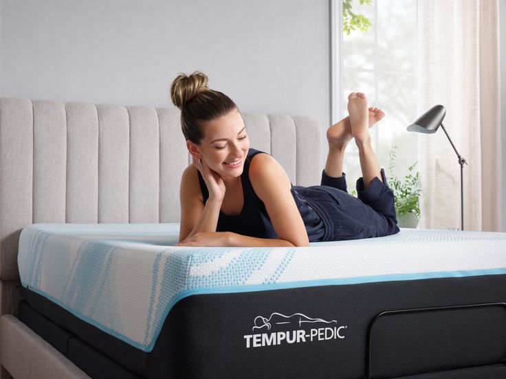 a woman laying on top of a tempurpedic mattress