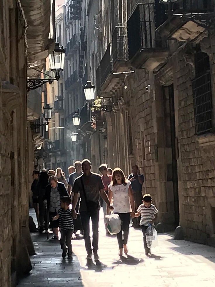 people are walking down an alleyway in the old city with stone buildings on either side