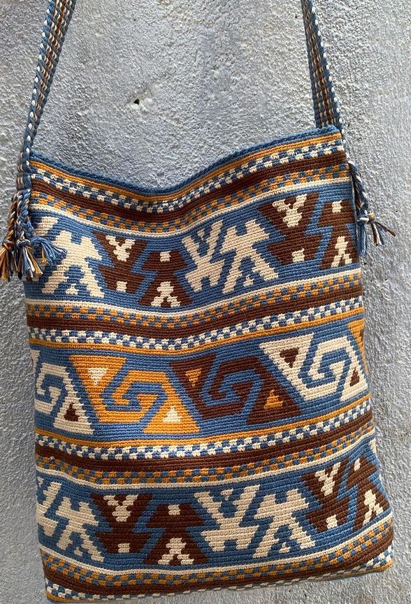 a handbag hanging on the wall in front of a gray wall with blue and orange designs