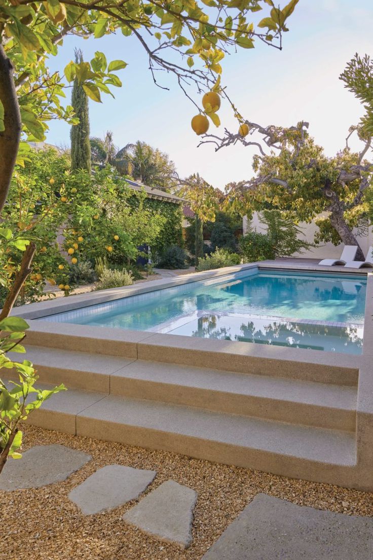 an outdoor swimming pool with steps leading up to it and trees in the back ground