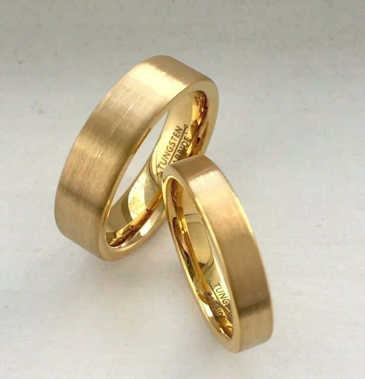 two gold wedding rings sitting on top of each other