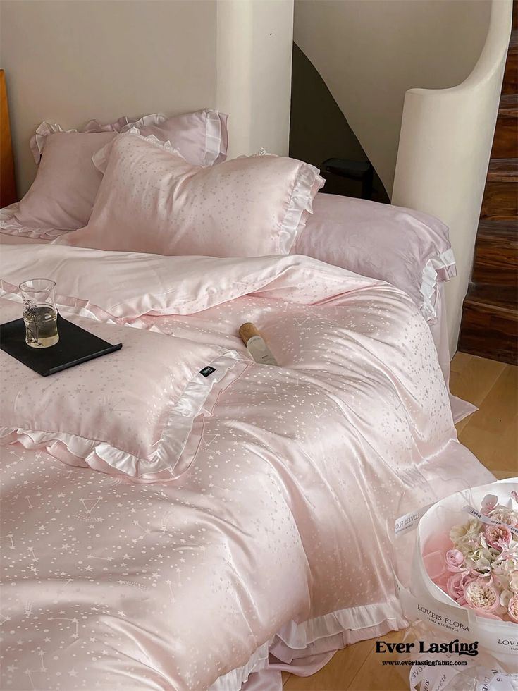 a bed with pink comforters and pillows on it