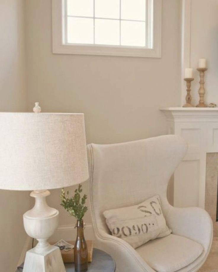 a white chair sitting next to a fireplace with a lamp on it's side