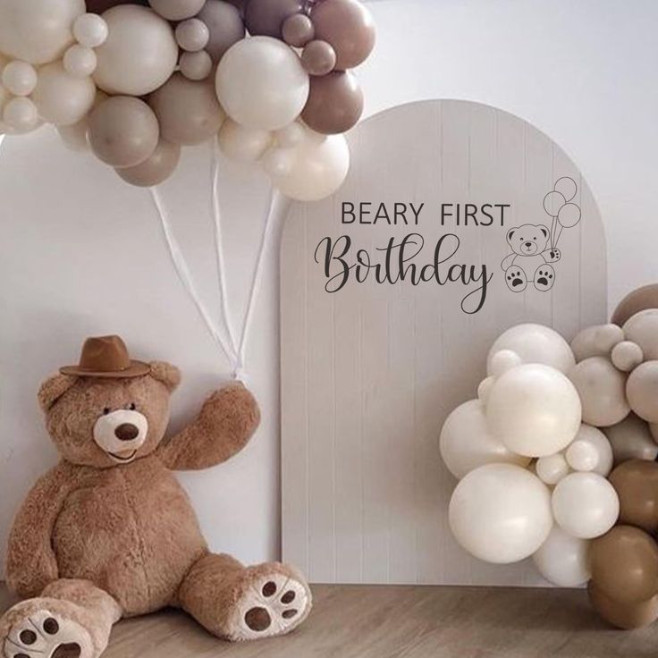 a teddy bear sitting next to balloons and a sign that says, bear first birthday