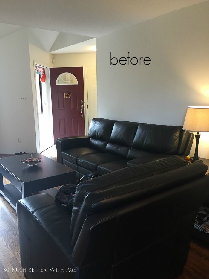 a living room with black leather couches and a coffee table in front of the door