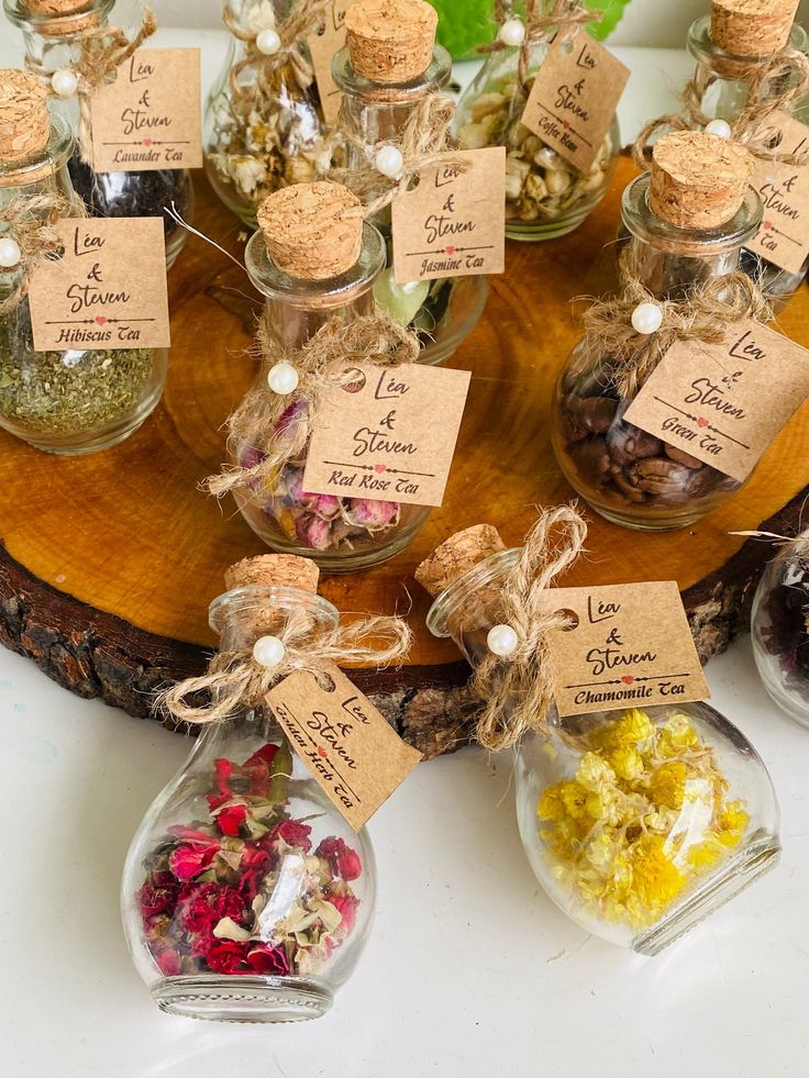 small glass bottles filled with different types of candies on a wooden tray and tied with twine