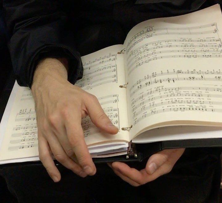 a person is holding an open book with music sheets on it and their hands are in the pages