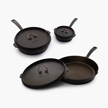 three black pots and pans on a white surface