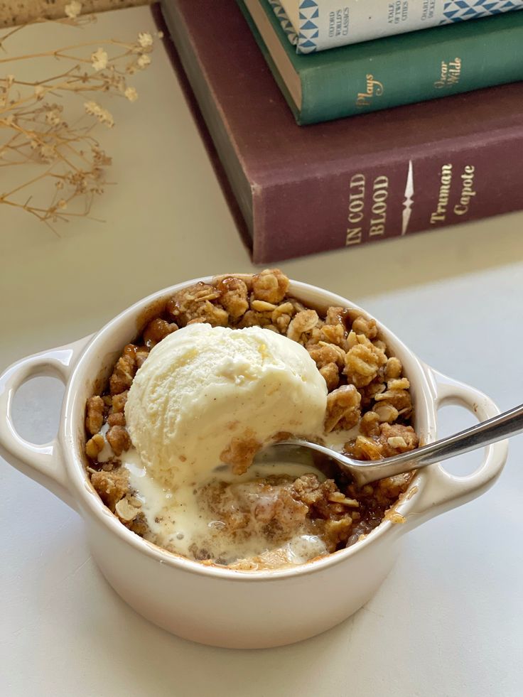 a scoop of ice cream sits in a bowl next to some books on a table