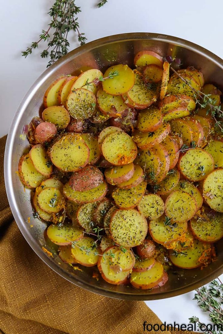 a pan filled with potatoes and herbs on top of a table