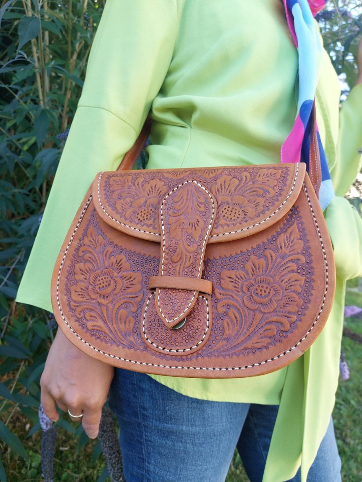 This bag was 100% handcrafted by Indonesian artisans. The relief patterns are very carefully worked into the leather with a high level of detail and that's why the bag is very unique. The bag also has a compartment inside. It can be closed Pocket with a buckle closure. Material: cowhide leather Color: brown Size: 25cm x 19cm x 9cm Artisan Hand Tooled Crossbody Satchel, Artisan Hand-tooled Crossbody Satchel, Artisan Hand Tooled Crossbody Saddle Bag, Traditional Leather Saddle Bag, Bohemian Hand Tooled Saddle Bag, Traditional Leather Saddle Bag With Adjustable Strap, Traditional Hand Tooled Saddle Bag, Handmade Artisan Brown Saddle Bag, Artisan Handmade Brown Saddle Bag