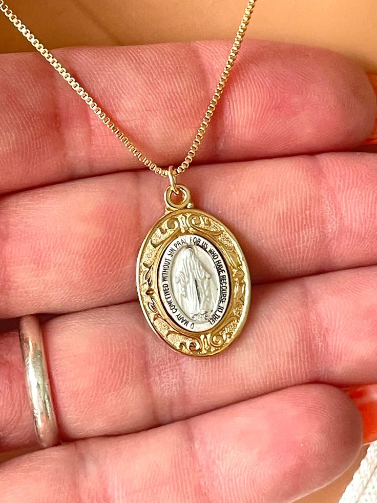 This is a beautiful oval, Mary miraculous medal made of two tone 16 karat gold over 925 sterling silver. Pendant Size 23x16mm. Chain shown is 16kt gold filled shiny box chain necklace with spring clasp.  May choose this chain in 925 Sterling Silver or in 14 karat gold filled shown.  Model is wearing 18" length in photos.  Choose which color chain you want and what length in the drop-down list. Comes in a gift box ready to present.  This necklace is stunning, more beautiful in person! White Gold Necklace With Miraculous Medal For Gift, Yellow Gold Miraculous Medal As Gift, White Gold Necklace With Miraculous Medal As Gift, Oval Spiritual Jewelry For Commemoration, Spiritual Oval Jewelry For Commemoration, Gold Jewelry With Miraculous Medal For Memorial, Gold Miraculous Medal Jewelry For Memorial, Silver 14k Gold Locket Necklace As Gift, Gold Oval Pendant Spiritual Jewelry