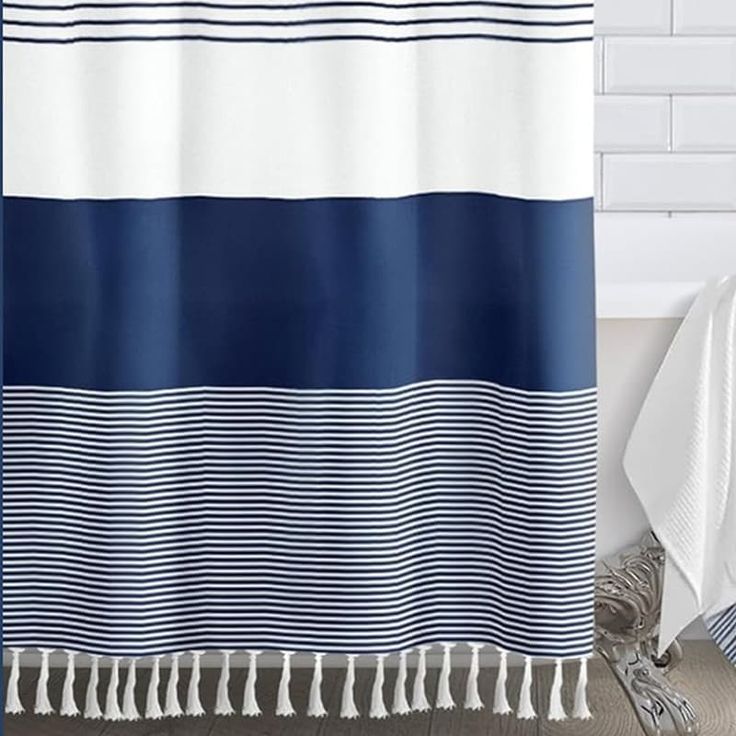 a blue and white striped shower curtain next to a bathtub with silverware on the floor