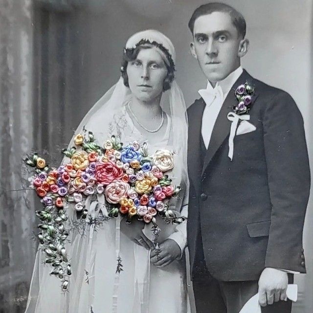 an old black and white photo of a man and woman dressed in wedding attire with flowers