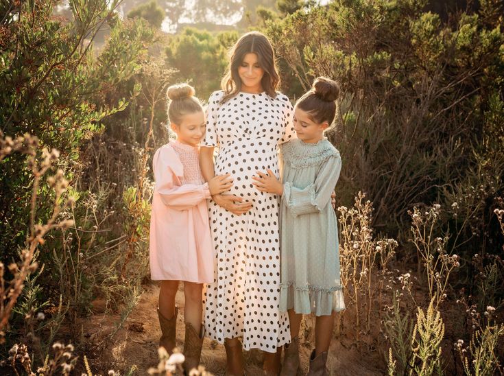 two women and three children are standing in the woods with their arms around each other