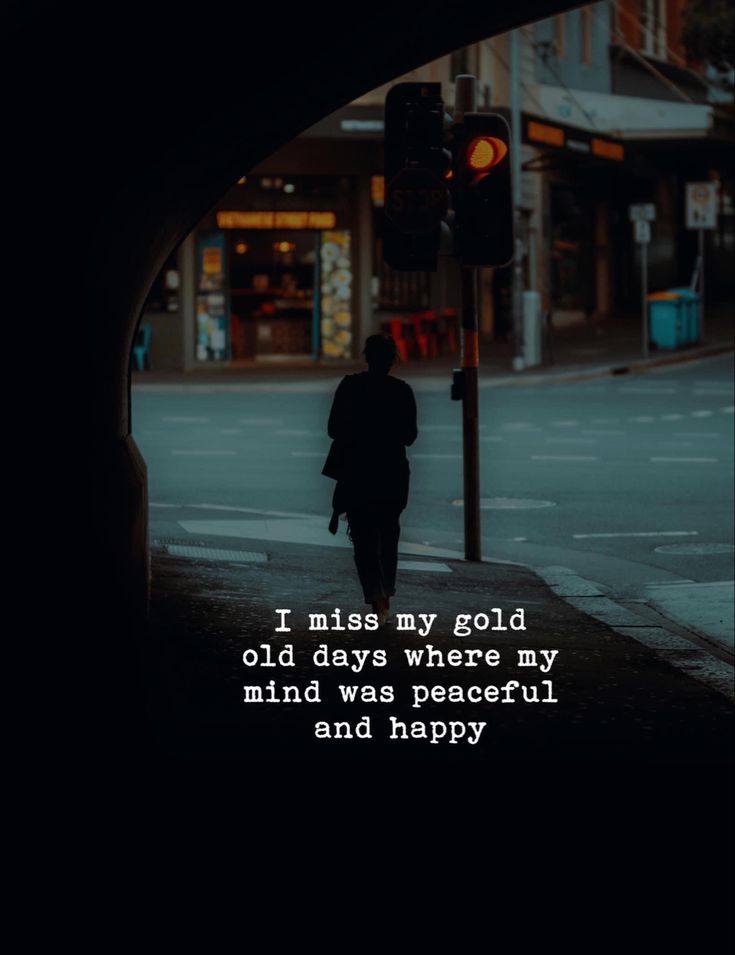 a person walking down the street in front of a traffic light with a quote on it that reads, i miss my gold old days where my mind was peaceful and happy