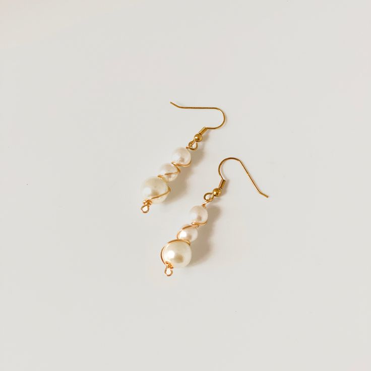 the gold and white pearl drop earrings are shown on a white surface, with small pearls hanging from them