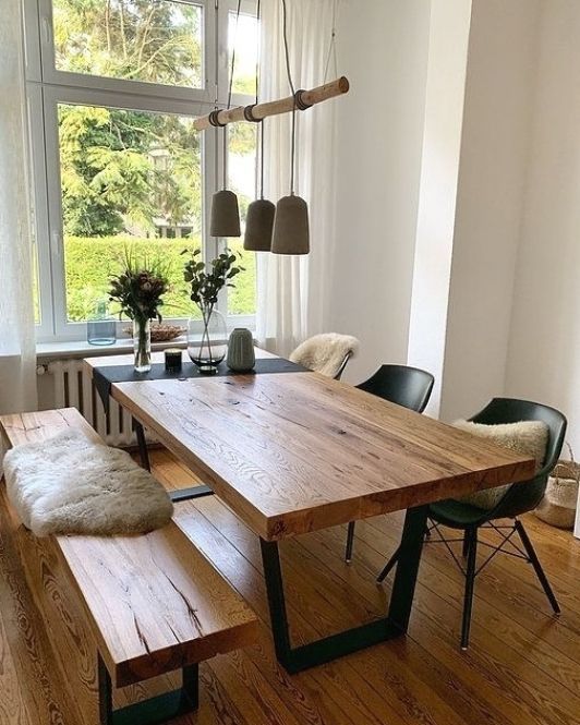 a wooden table sitting in front of a window next to two black chairs and a bench