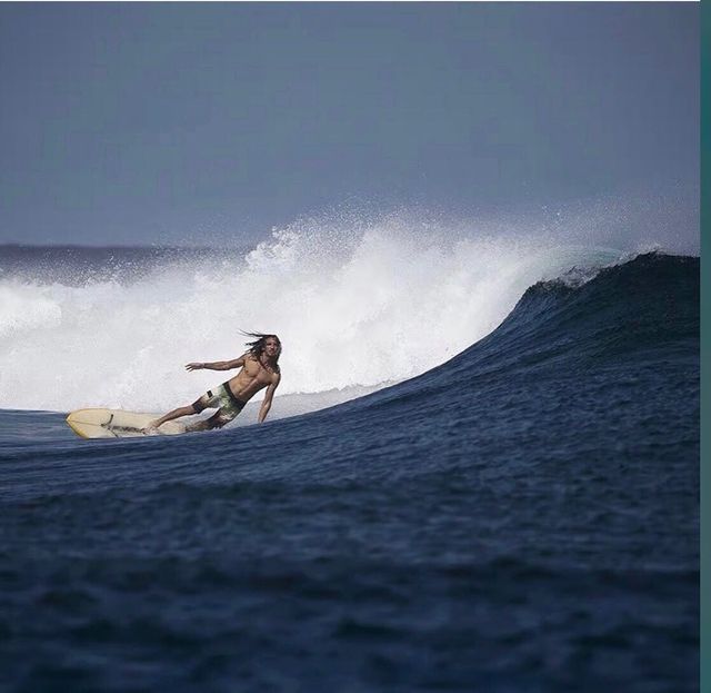 a man riding a wave on top of a surfboard in the middle of the ocean