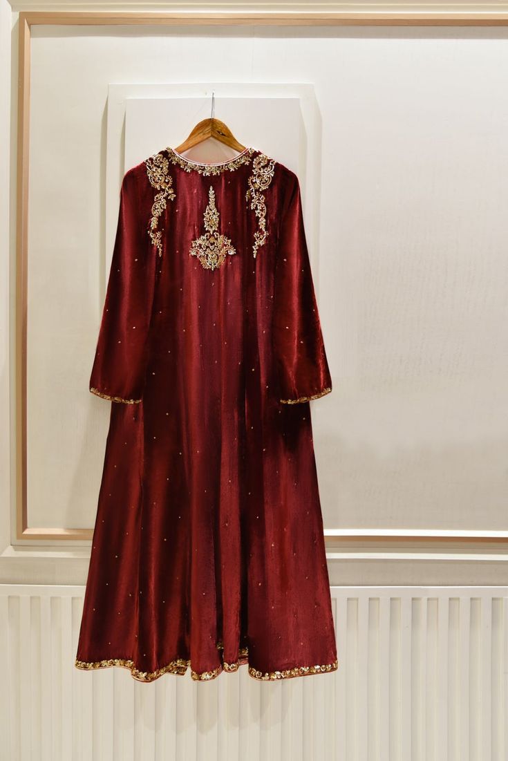 A heavily embellished beautiful three piece on pure dark maroon velvet, adorned with the most stunning hand/ada work of dabka, naqshi, sequins and crystals done by our skilled artisans. Paired with a heavily embellished pure velvet shawl and flappers featuring matching border. The length of the long angrakha is 48 inch Pakistani Velvet Suits, Pakistani Cotton Suits, Velvet Pakistani Dress, Velvet Shawl, Gota Work, Dark Maroon, Cotton Suits, Suit Designs, Bridal Designs