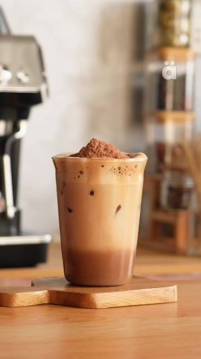 a cup of coffee sitting on top of a wooden table next to an espresso machine