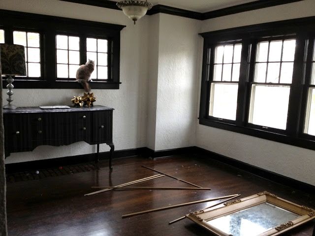 an empty room with wooden flooring and two windows in the corner, one has a mirror on top of it